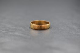 An 18ct gold band, having rubbed engraved decoration, marked 18, ring size N-O, 2.2g