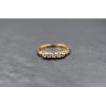 A yellow metal 5 stone diamond ring stamped 18ct having five small diamonds in a gallery mount on an