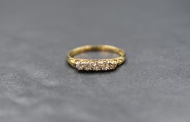 A yellow metal 5 stone diamond ring stamped 18ct having five small diamonds in a gallery mount on an
