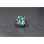 A 9ct gold blue topaz ring by QVC, the central cushion cut blue topaz within a halo surround of