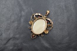 An Edwardian 9ct gold red spinel and seed pearl set locket pendant, the central oval locket in a