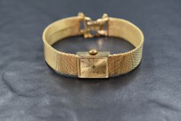 A 14ct gold Baume & Mercier wristwatch, the rectangular golden dial having baton numerals, on a 14ct