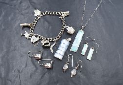 A white metal charm bracelet stamped STG having a padlock clasp and seven charms, mainly of