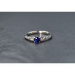 An 18ct white gold sapphire and diamond ring having a central sapphire, approx 0.25ct flanked by two