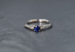 An 18ct white gold sapphire and diamond ring having a central sapphire, approx 0.25ct flanked by two