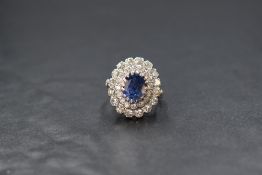 A white metal (insurance valued as platinum) sapphire and diamond set cluster ring, the central oval
