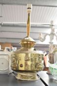 An early 20th century brass lamp decorated with Buddha figures and raised on a circular footed base,