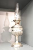 An early 20th century metal oil lamp raised on a circular base and decorated with geometrical