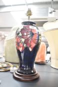 A Moorcroft pottery lamp of lobed form decorated with floral patterns on a colbart blue ground,
