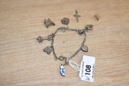 A white metal charm bracelet having seven charms with an additional three loose including an