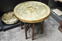 An early 20th century middle eastern circular brass top coffee table having folding wooden base