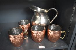 A metal pitcher having shaped handle and spout, sold together with 4 copper style mugs