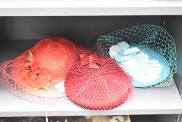Three ladies fascinators or wedding hat / headpieces, each with a net veil, in red, burgundy and