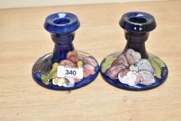 A pair of Moorcroft pottery candlesticks decorated with floral patterns on a colbert blue ground,