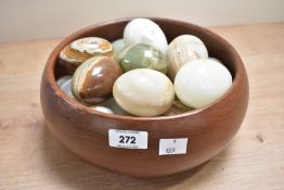A collection of nineteen turned onyx eggs contained in a turned teak bowl of traditional design
