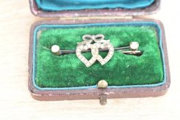 A white metal and seed pearl set brooch, the two interlocking hearts set with split seed pearls