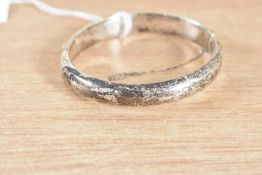An Elizabeth II HM silver hinged bangle, having decorative scroll engraving, with safety chain (af)