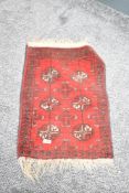 A small red rug decorated with geometrical patterns, L66cm