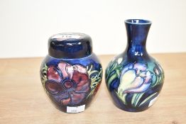 A Moorcroft pottery ginger jar with cover, decorated with floral patterns on a colbart blue