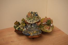 A group of four Liliput lane models on presentation stand to include 'Low Tide at Anchor Bay' and '