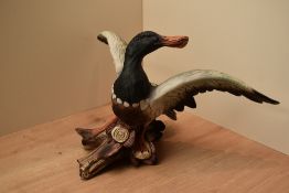 A large ceramic painted mallard duck study perched on logs, measuring 24cm x 42cm approximately.