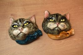 A pair of amateur porcelain cat wall masks wearing blue and orange collar/bow ties.
