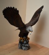 A large resin painted Gold Eagle study perched on a cliff edge, having faded marking to base
