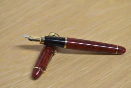 A Parker Duofold Lucky Curve button fill fountain pen in Mauve Moire with a two cap bands on a