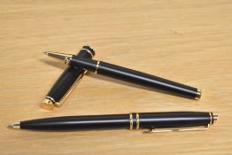A boxed matte black and gold ballpoint and rollerball pen set