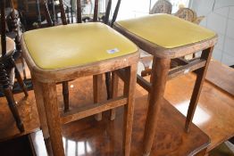 A pair of 1950's stools with yellow rexine seat coverings