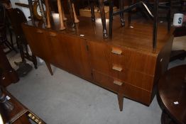 A mid-century teak sideboard having two cupboard doors, three drawers and raised on tapered legs,