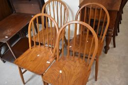 A set of four elm seated spindle back chairs in the manner of Ercol