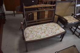 An Arts and Crafts style two seater settee having inlaid decoration and upholstered seat, L102cm