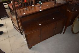 A mid-century mahogany style sideboard having book shelf below three cabinet doors decorated with