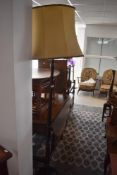 A wooden standing floor lamp having fabric shade and circular base raised on three ball feet