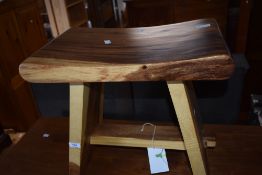 An imported wood stool, the slightly concaved rectangular seat on trestle type supports linked by