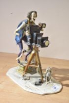 A continental porcelain study of a photographer or film maker having damage to his right arm and
