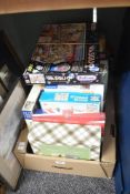 A collection of assorted jigsaw puzzles and a puzzle mat.
