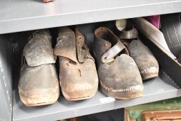 Two pairs of early 20th century leather clogs and a natural ergonomic walking stick.