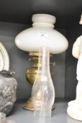 A vintage brass effect oil lamp having glass shade and chimney