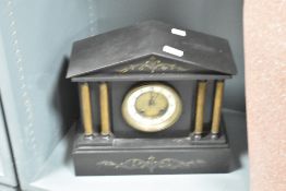 A Victorian black slate mantel clock, of architectural form with columns flanking the circular