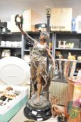 An early 20th century table lamp of a spelter female figure raised on a circular base, h52cm