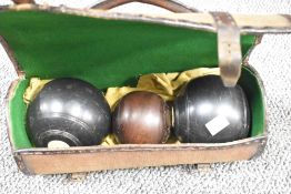 A canvas and leather bowling bag and three bowls