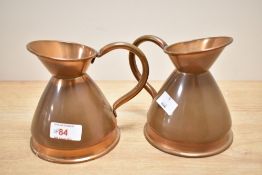 A pair of copper measuring jugs having shaped handle and spout, h12.5cm