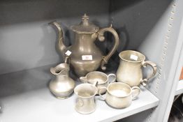 A pewter tea pot having shaped spout and handle, h26cm, sold together with a cream jug and tankard