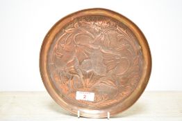 A copper charger in the Art Nouveau style decorated with floral patterns, w21cm