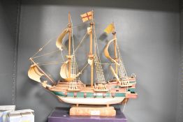 A vintage hand-painted miniature model ship on wooden base, measures 44cm 47cm.