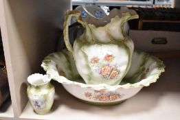 A Limoges style pitcher and basin having gilt edges and floral patterns on a green ground, sold