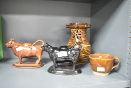 A 19th Century slipware puzzle jug, height approx 21cm, sold with two traditional cow creamers and a