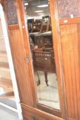 A Victorian mahogany mirror door wardrobe having dentil cornice, urn and foliate carved panel